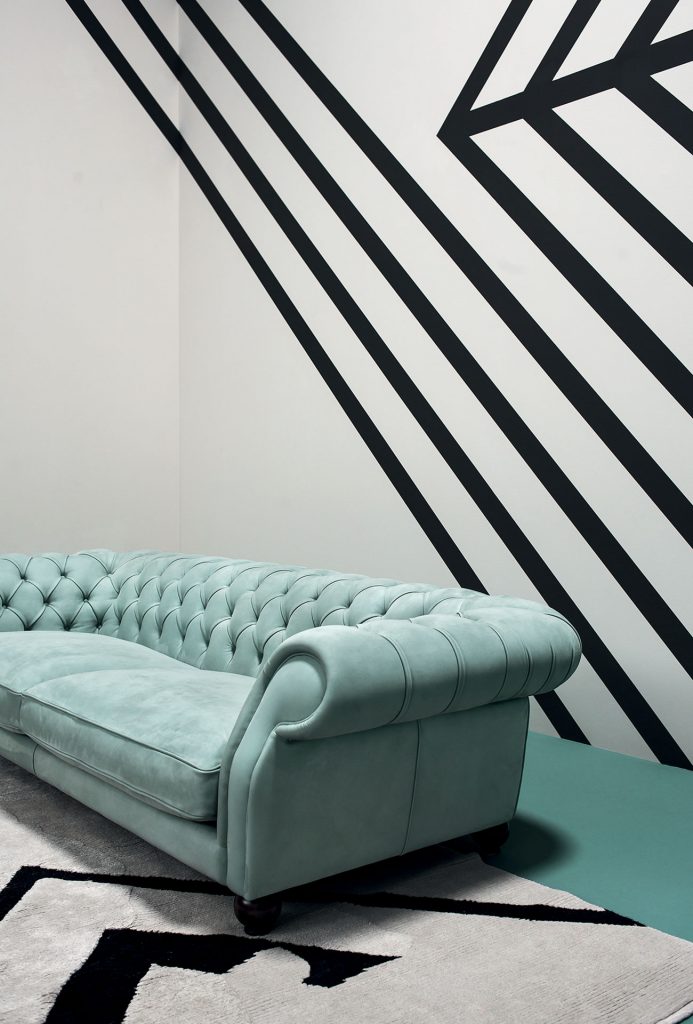 Diana Chester Sofa. Frame in poplar wood. Feet in walnut dark brown. Blue seat cushions in goose down with pad in polyurethane foam insert. torsion springs in back and armrests in a dining room.