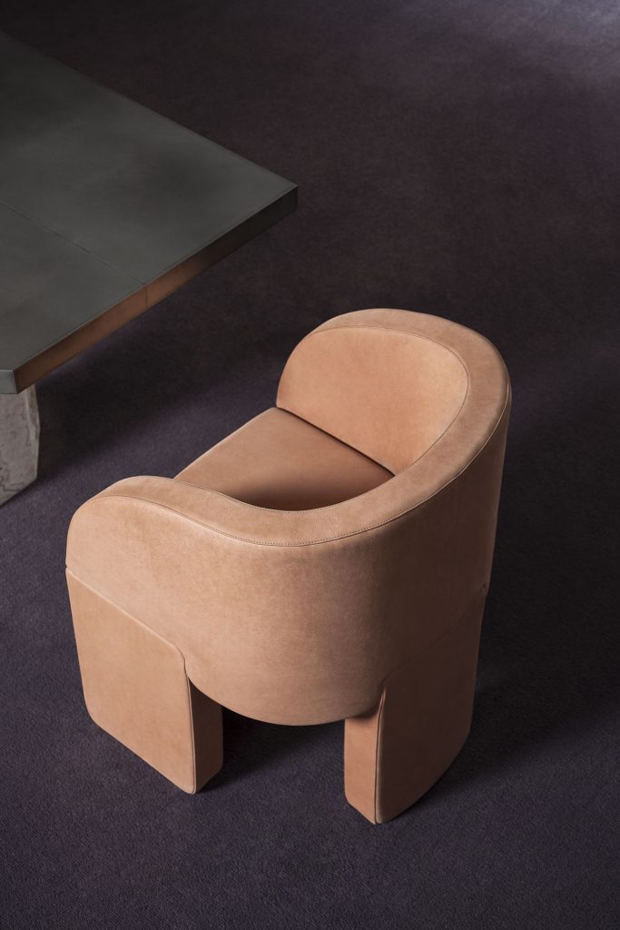 Armchair made of three-legged base with velvet fabric in an orange tone in a living room