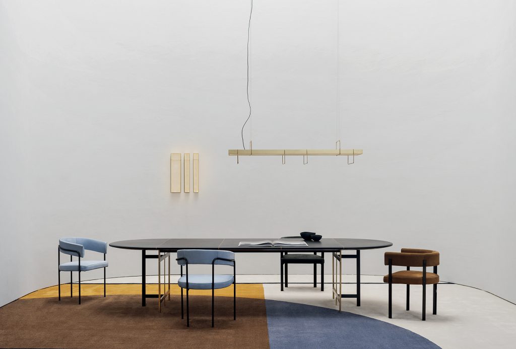 A Placè Dining Table. Base in brass with bronzing oxidation on the flat part and satin finish on the thickness, with wax finish. Leg connection plate in matte black metal. MDF top with reinforcing black leather-covered aluminium sheets. Decorative inserts in satin-finished brass with wax finish.