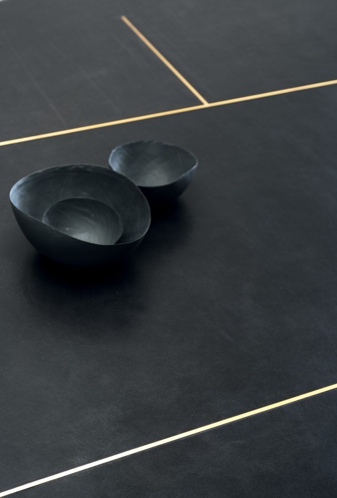 black metal. MDF top with reinforcing black leather-covered aluminium sheets. Decorative inserts in satin-finished brass with wax finish.