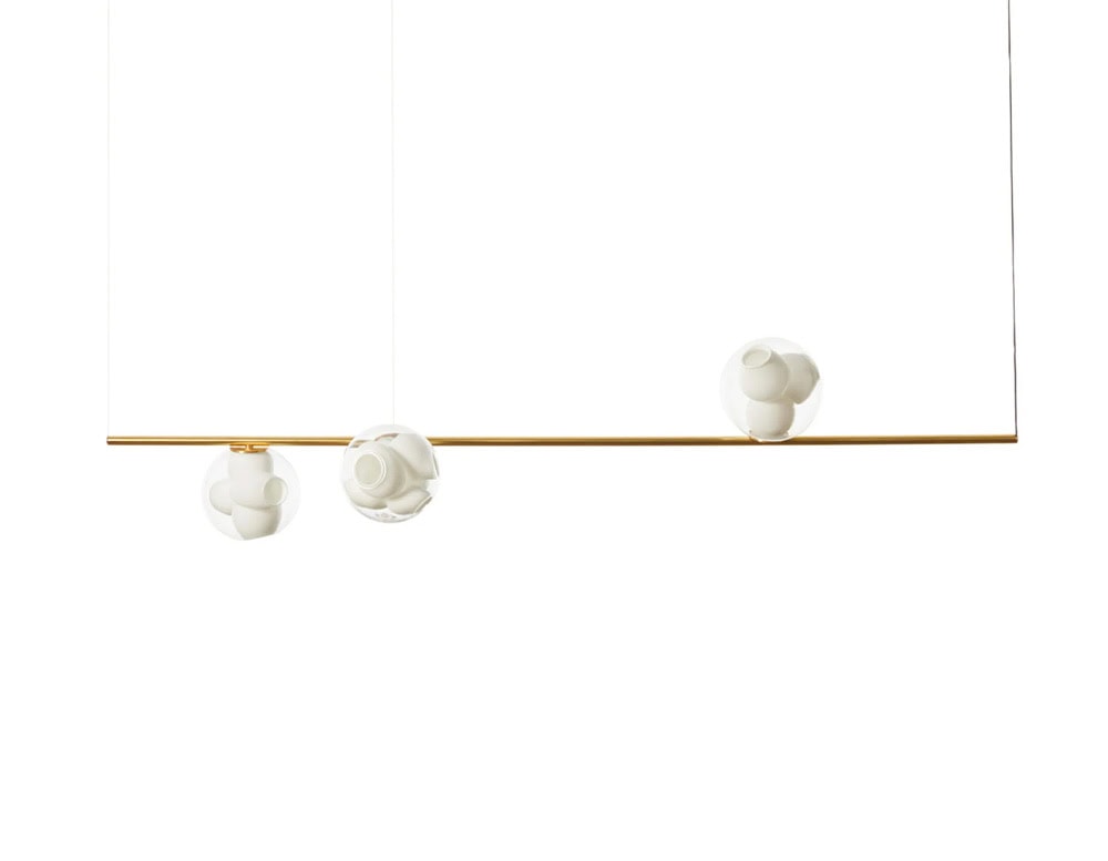 Boc Stem Suspended Ceiling Light shows three frosted globes resting along a brass rod. The play of balance and form highlights the sculptural quality of the light fixture while maintaining elegance and simplicity.
