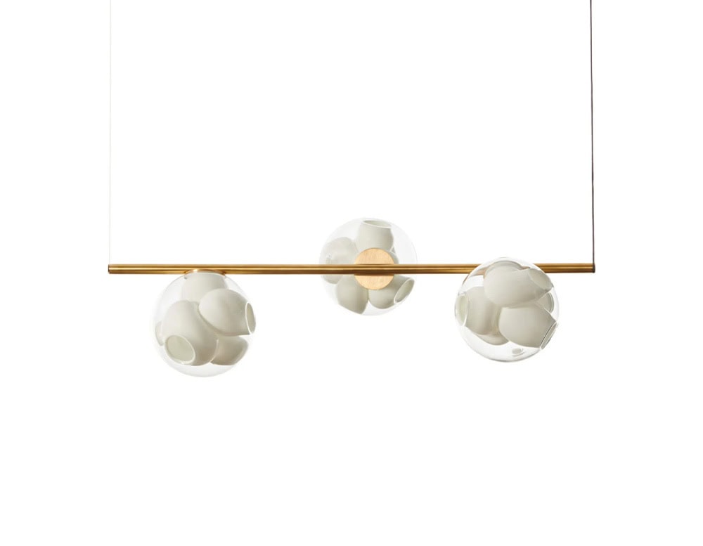 Boc Stem Suspended Ceiling Light features a trio of transparent spheres with matte white interior forms. They sit along a gold-toned rod, creating a clean, minimal look suspended against a stark white backdrop.