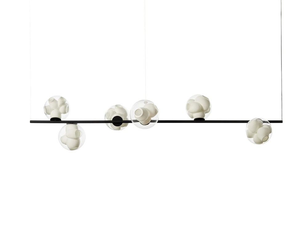 Boc Stem Suspended Ceiling Light features six spherical diffusers along a sleek black rod. The glass orbs house intricate ceramic elements, producing a bold linear suspension that merges sculptural clarity with ambient warmth.