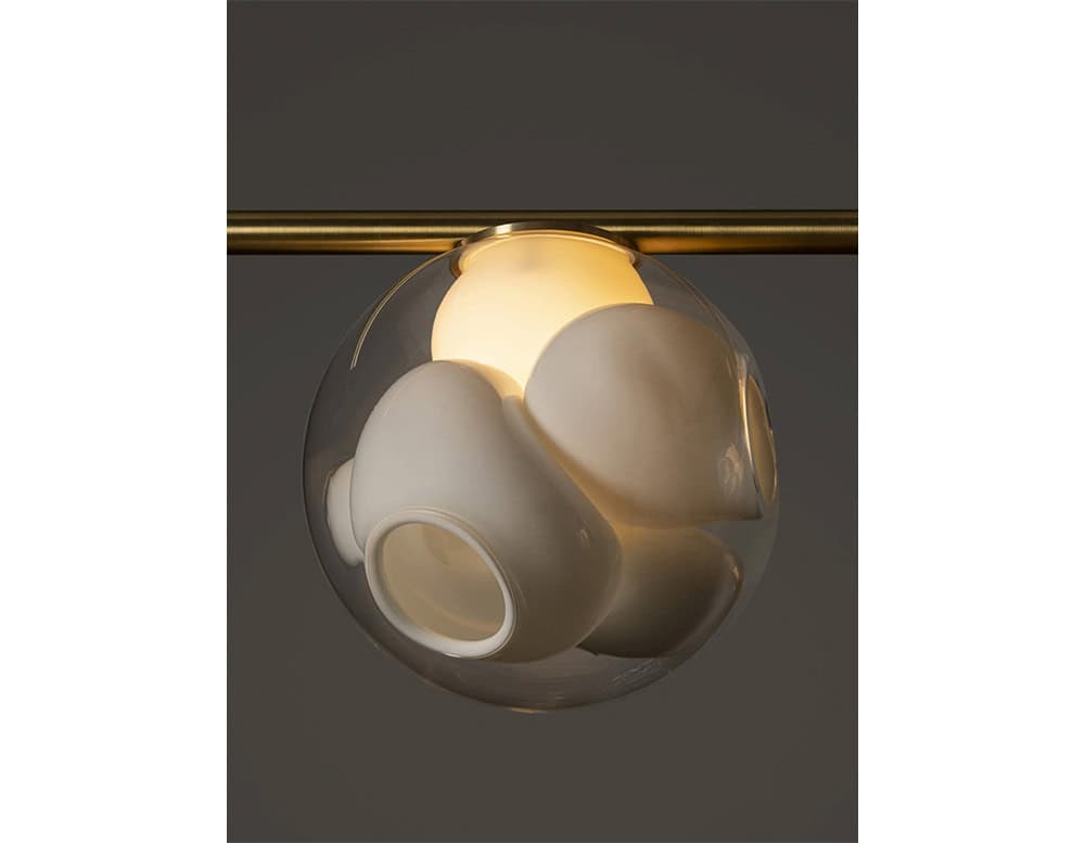 Boc Stem Suspended Ceiling Light highlights the intimacy of a single lit globe. Each orb holds a cluster of opaque ceramic forms, glowing softly through the transparent outer shell, creating a sculptural play of light and shadow.