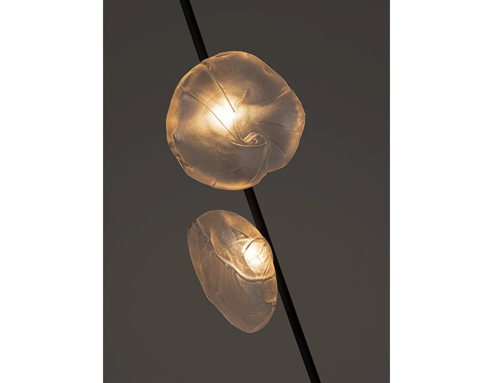 Boc Stem Column Floor Light detail of the sculptural glass elements against a dark stem, radiating a warm, ambient glow. The artisanal glasswork, with its unique folds and swirls, adds a poetic dimension to the linear design of the floor lamp.
