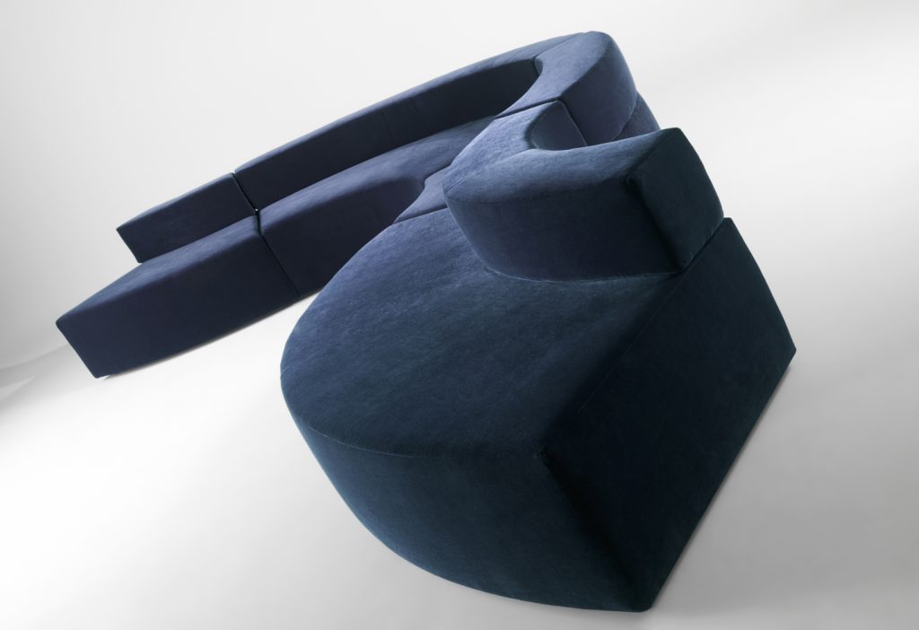modular sofa made on a wooden base and covered in a blue snake-shaped fabric on a white background