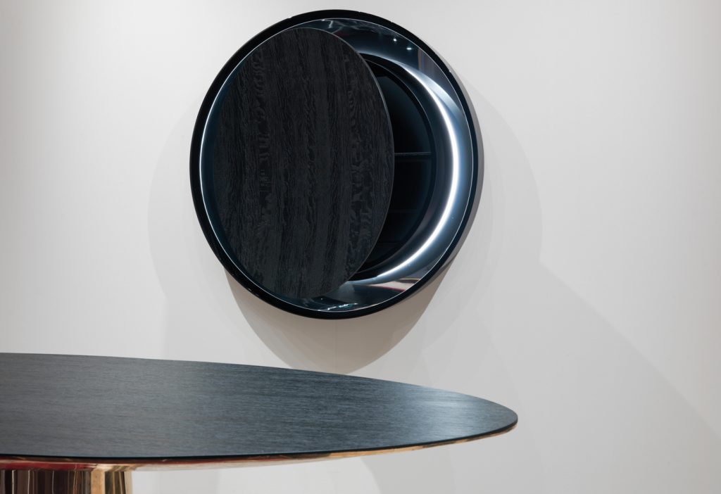 round mirror made of a wooden base covered in polished metal in a black colour tone