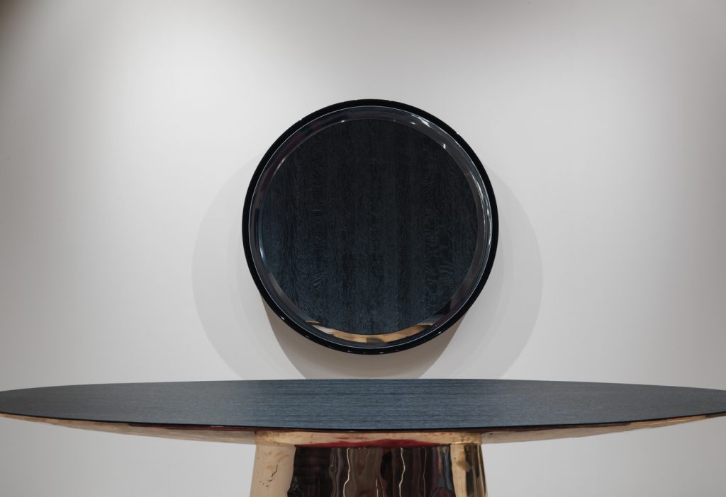 round mirror made of a wooden base covered in polished metal in a black colour tone