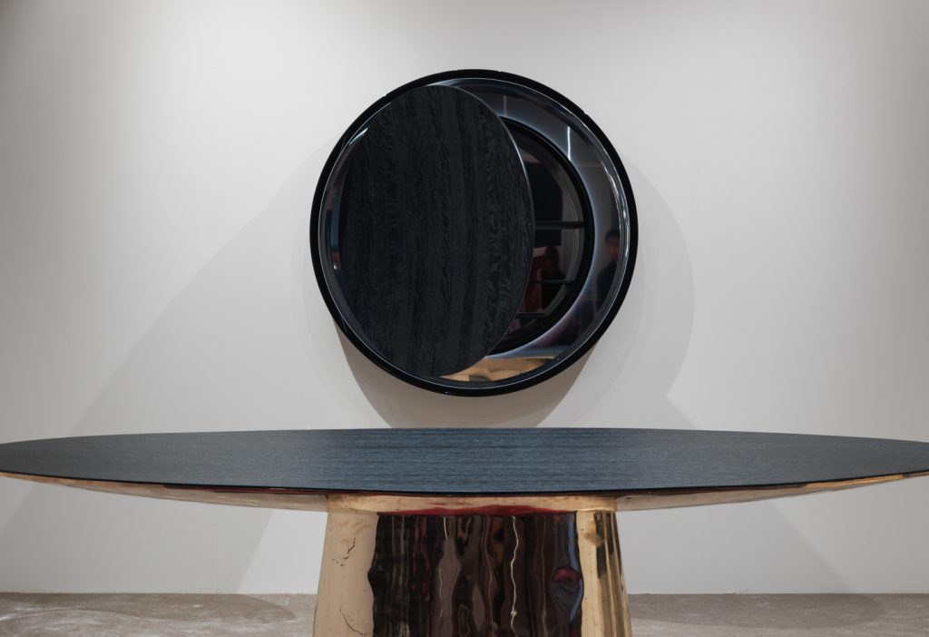 round mirror made of a wooden base covered in polished metal in a black colour tone
