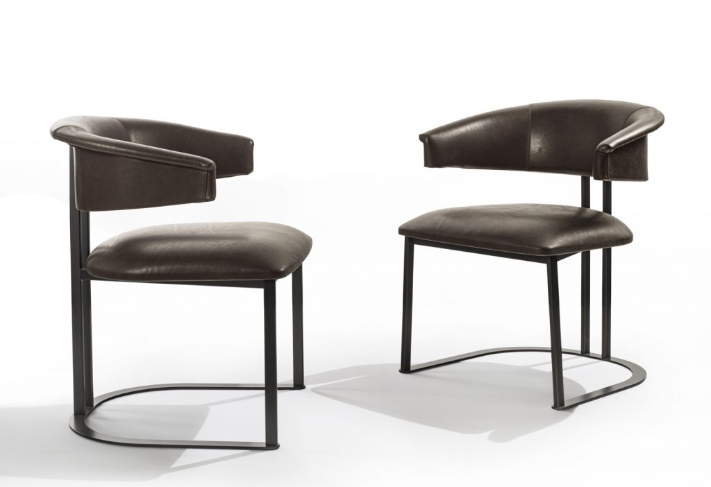 two curved armchairs made of an iron brass base and brown leather