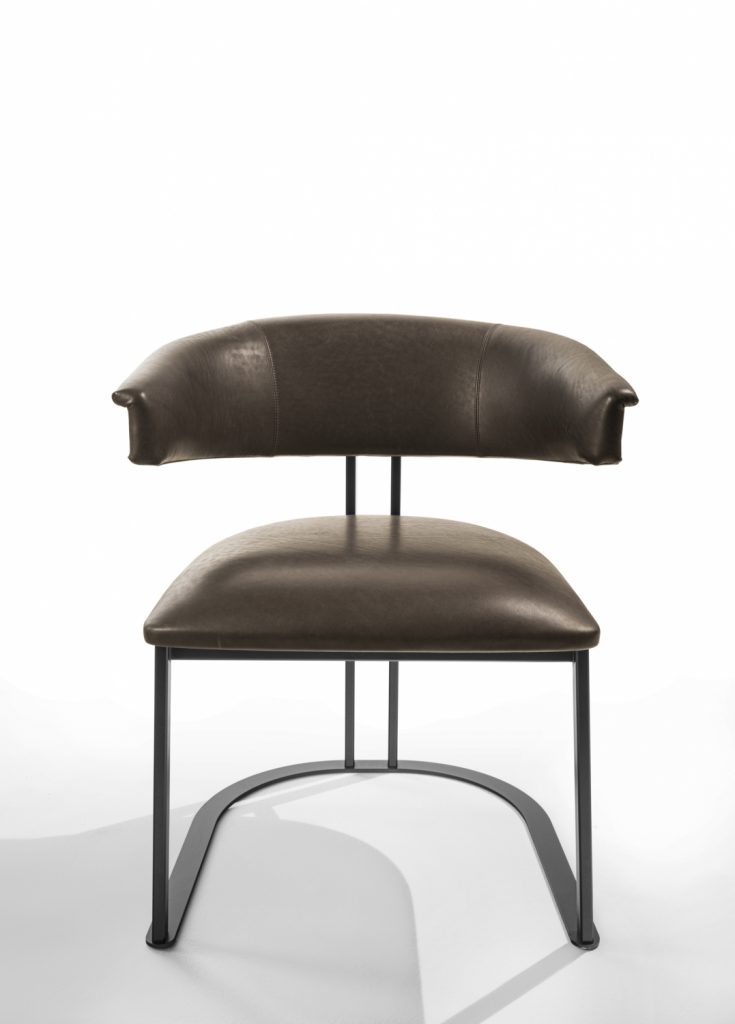 curved armchair made of brown leather and an iron and brass base on a white background