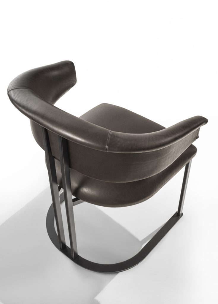 curved armchair made of brown leather and an iron and brass base on a white background