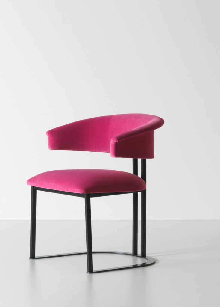 curved armchair made of pink leather and an iron and brass base on a white background