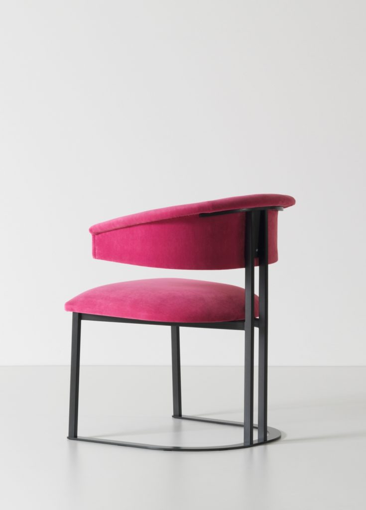 curved armchair made of pink leather and an iron and brass base on a white background