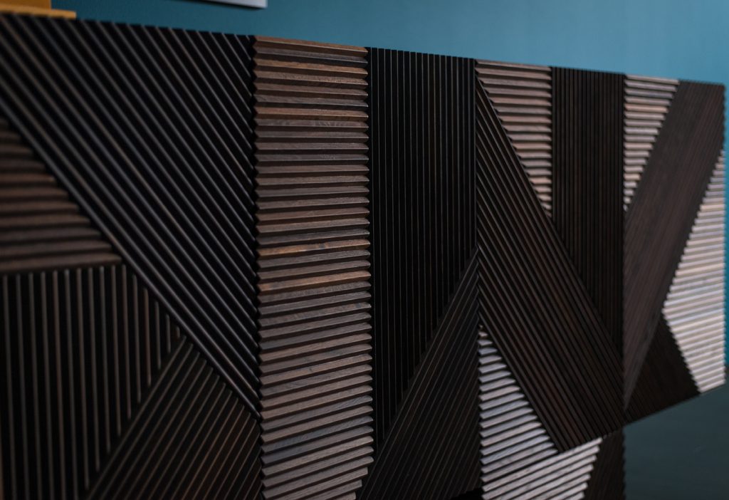 Closeup of Stripes Cabinet: Large cabinet with brown vertical striped pattern and multiple drawers in front of a blue wall.