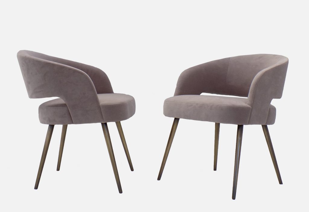 Two armchairs made of a wood and metal base upholstered in leather in a biege tone on a white background