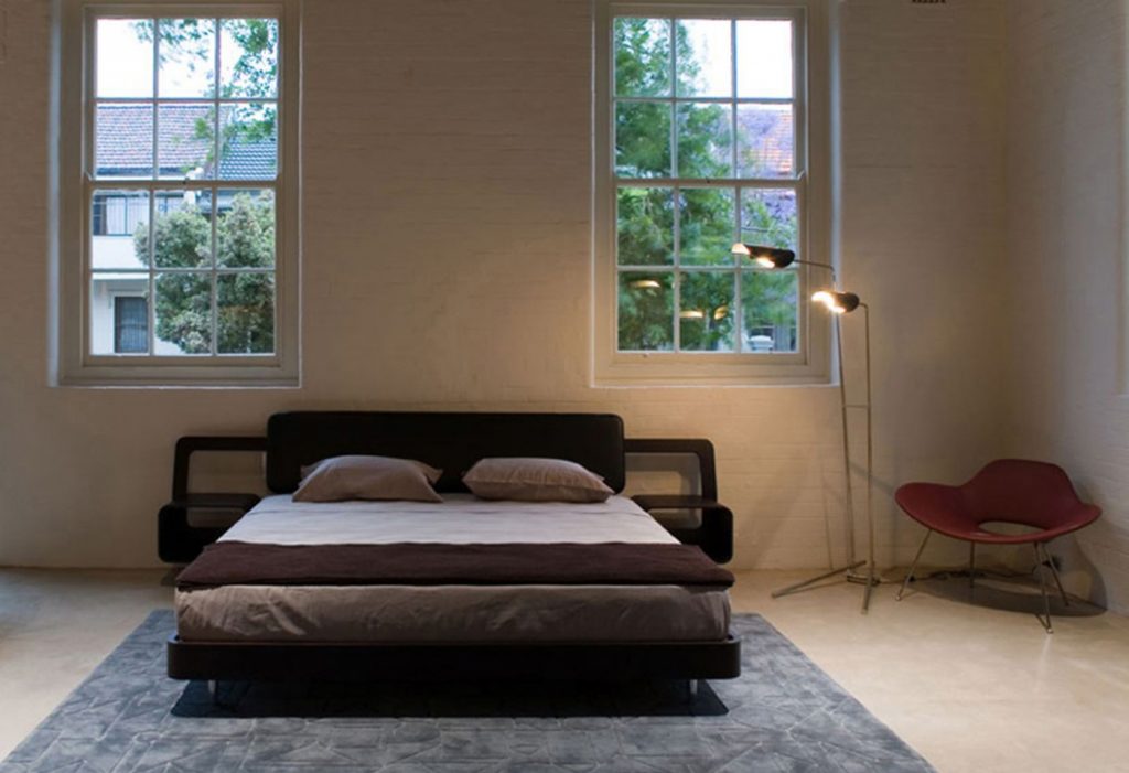 Bed made of a wooden base covered in leather in a white, black and brown colour tone in one room