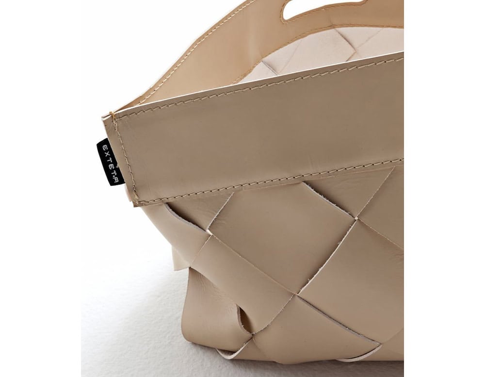 A detailed close-up of the 10th Baskets Tray showcasing its woven leather design structured edges and a small branded tag for a refined finish