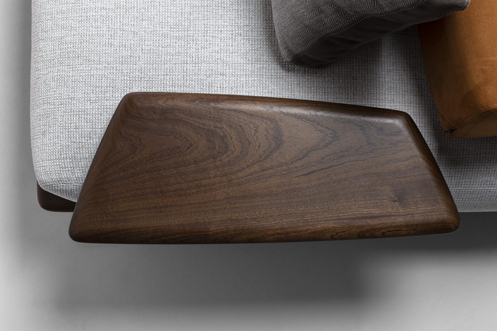 Closeup of Caprera Sofa: Large gray cushioned sofa with wooden frame and black legs.