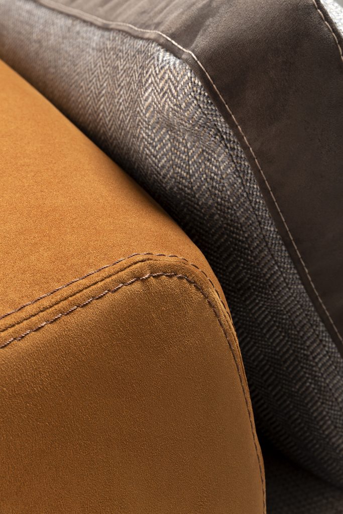 Closeup of Caprera Sofa: Large gray and orange cushioned sofa with wooden frame and black legs.