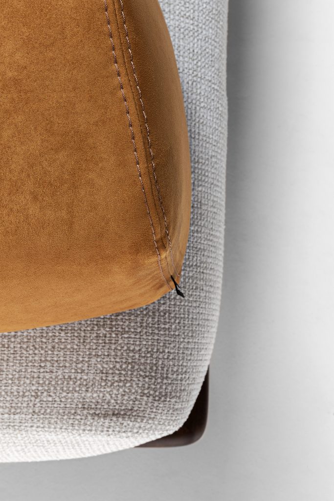 Closeup of Caprera Sofa: Large gray cushioned sofa with wooden frame and black legs on a white background.