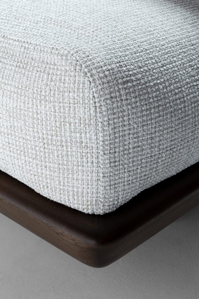 Closeup of Caprera Sofa: Large gray cushioned sofa with wooden frame and black legs on a white background.