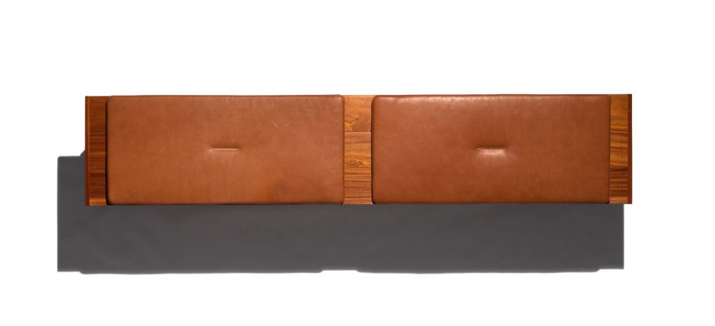 Caprera Chest: Large wooden storage chest with two legs and brown cushions on a white background.