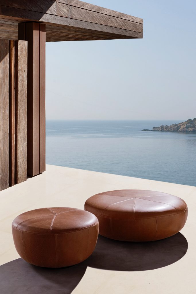 Two 10th Clove Poufs: Round pouf in brown leather fabric on a white background.