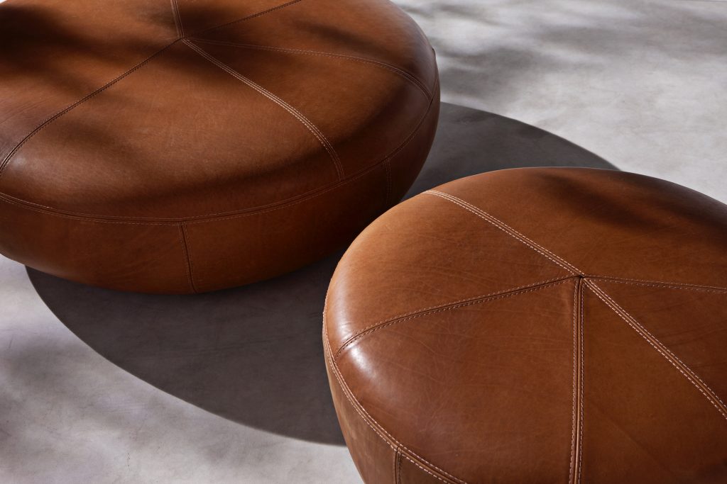 Two 10th Clove Poufs: Round pouf in brown leather fabric on a white background.