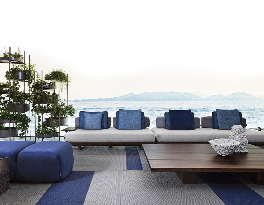 A stylish outdoor lounge featuring the Joint Rectangular Coffee Table modern seating blue-toned cushions and a stunning ocean view