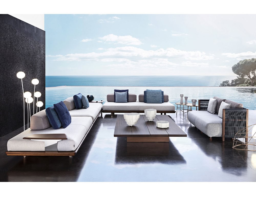 A luxurious outdoor lounge featuring the Joint Rectangular Coffee Table surrounded by modern seating plush cushions and an infinity pool overlooking the ocean