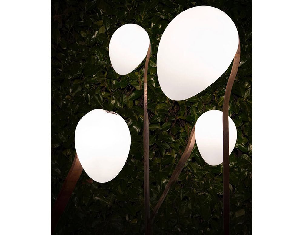 A close-up of a 10th Tree Light Outdoor Floor Light shows four white, orb-shaped diffusers on slender stems against a dark, blurred background