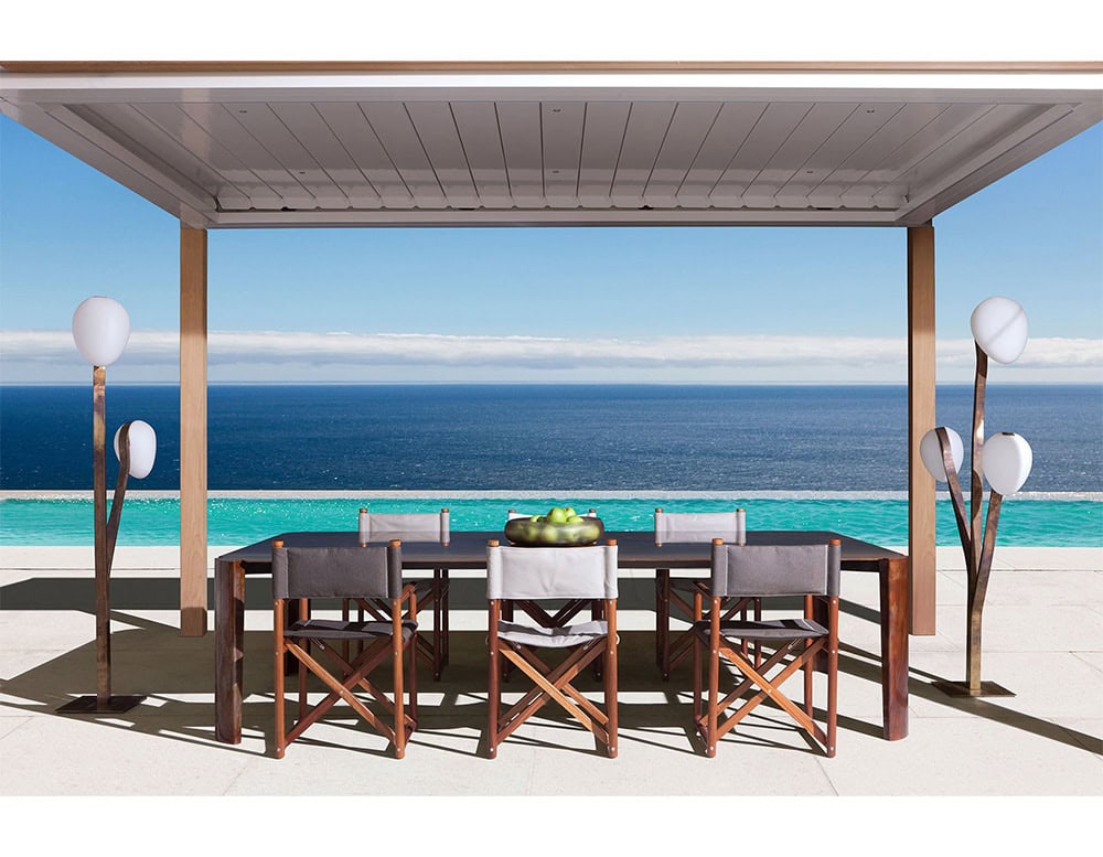 A 10th Tree Light Outdoor Floor Light with its multiple white, orb-shaped diffusers on slender stems is positioned on a patio overlooking the ocean under a clear blue sky
