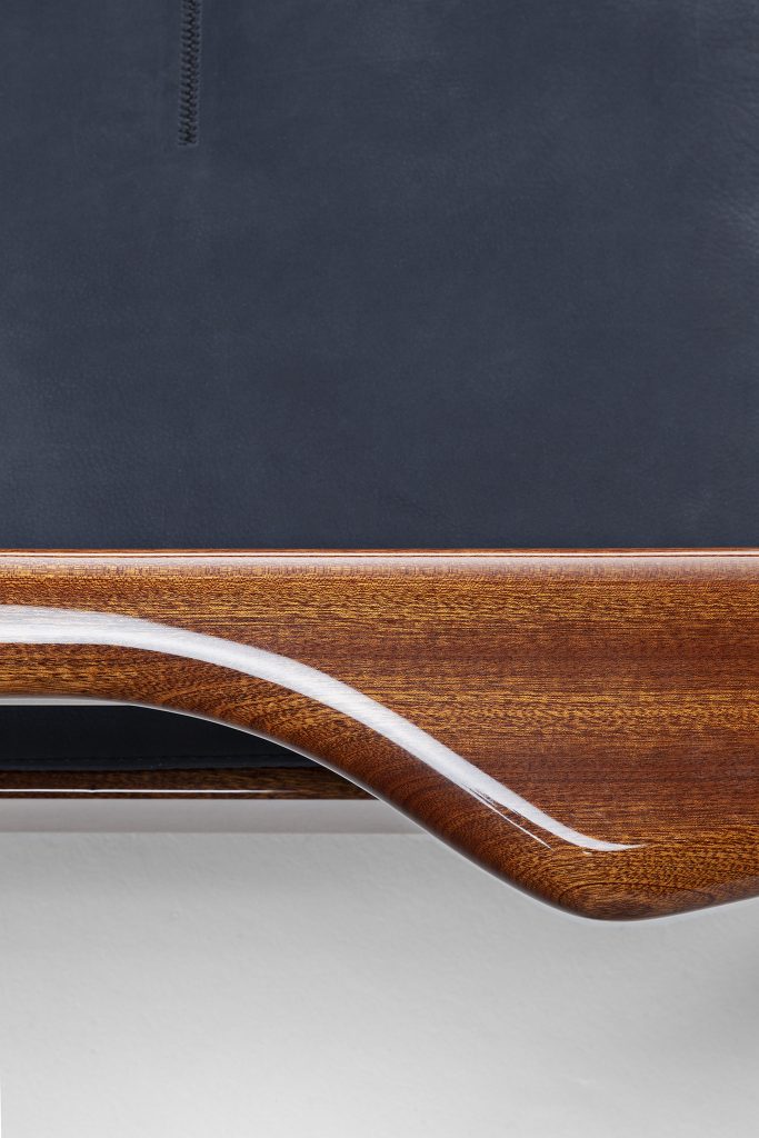 Closeup of Vieste Armchair: Wooden armchair with a gray cushioned seat with four legs on a white background.