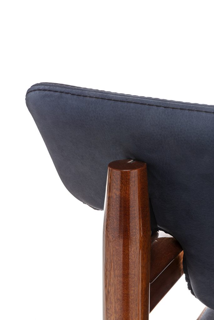 Closeup of Vieste Armchair: Wooden armchair with a gray cushioned seat with four legs on a white background.