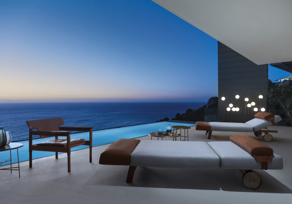 Vieste Armchair: Wooden armchair with a gray cushioned seat with four legs on a terrace.