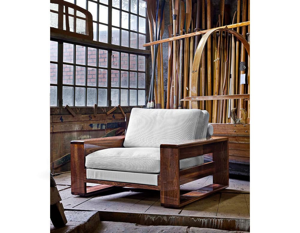 A rustic yet refined setting featuring the Bellagio Outdoor Armchair with a solid wooden frame plush cushions and an industrial-style backdrop