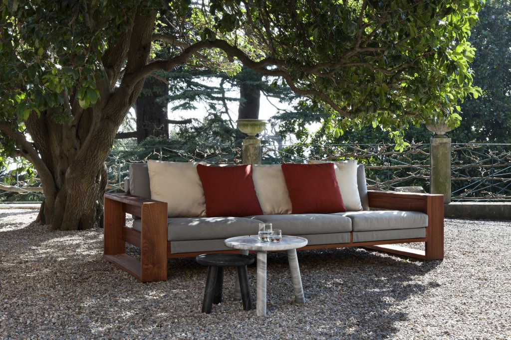 Bellagio Sofa cushioned in white fabric, strocture and two legs in brown wood on a terrace.