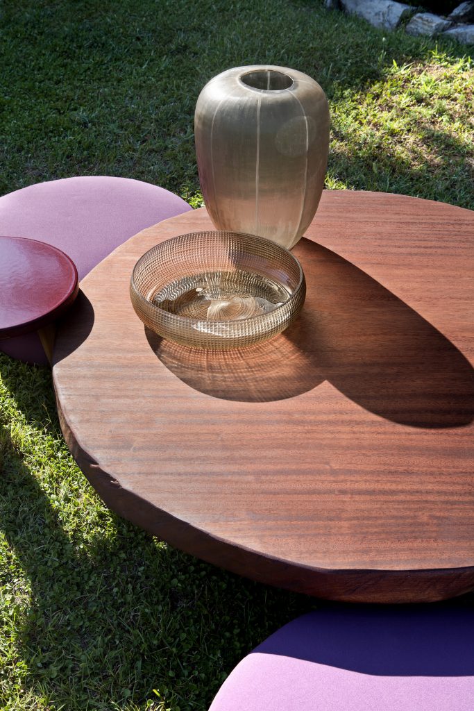 Closeup of Individual Mini Round: Small round brown table with a slim central pedestal on a terrace.