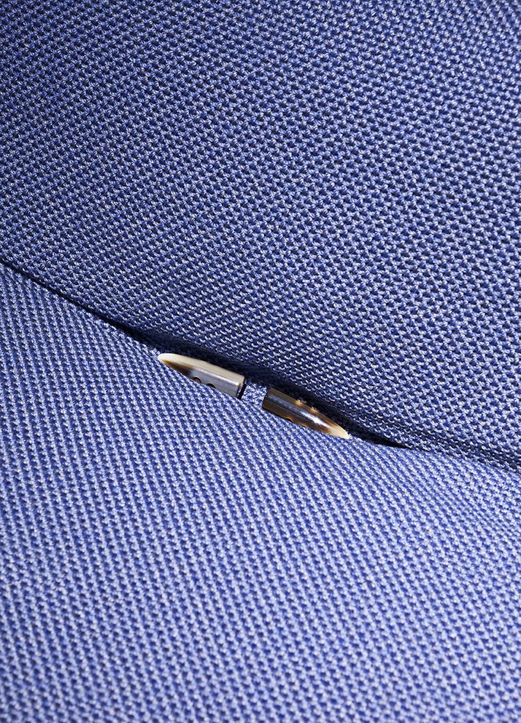 Closeup of brown Lerici Armchair with blue cushions.