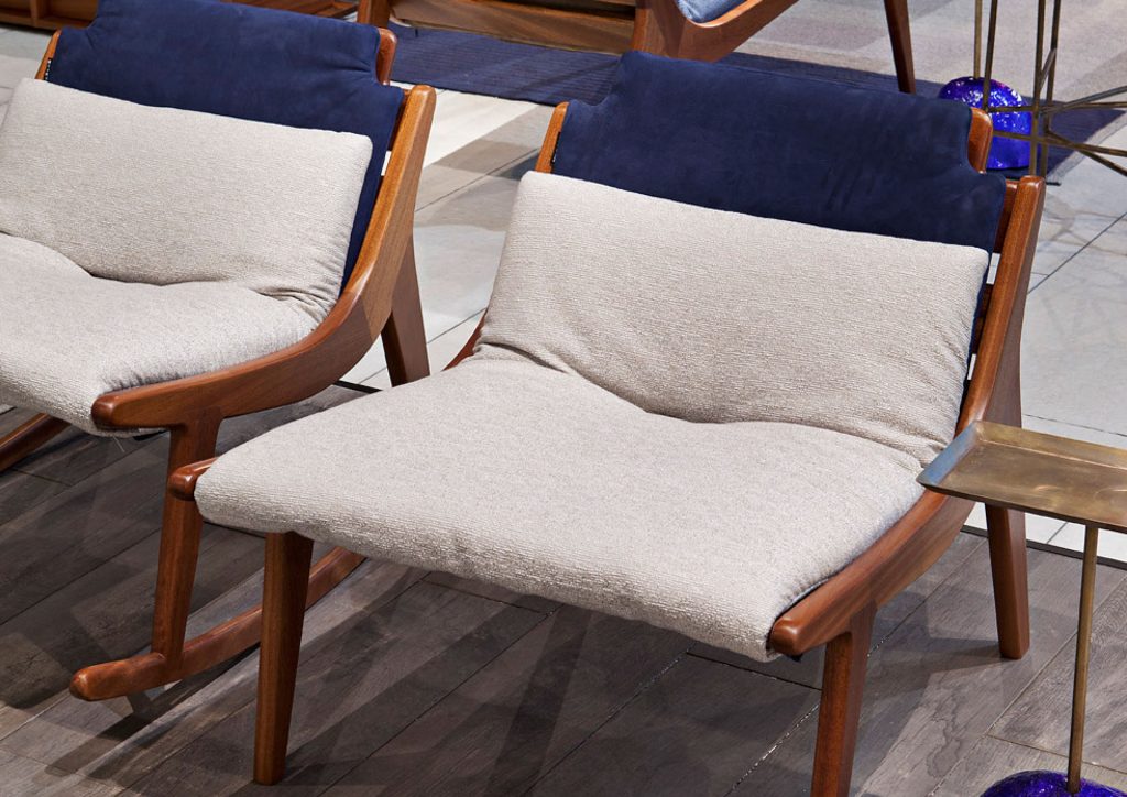 Two brown Lerici Armchairs with a curved backrest and thin legs with white cushions in a living room.