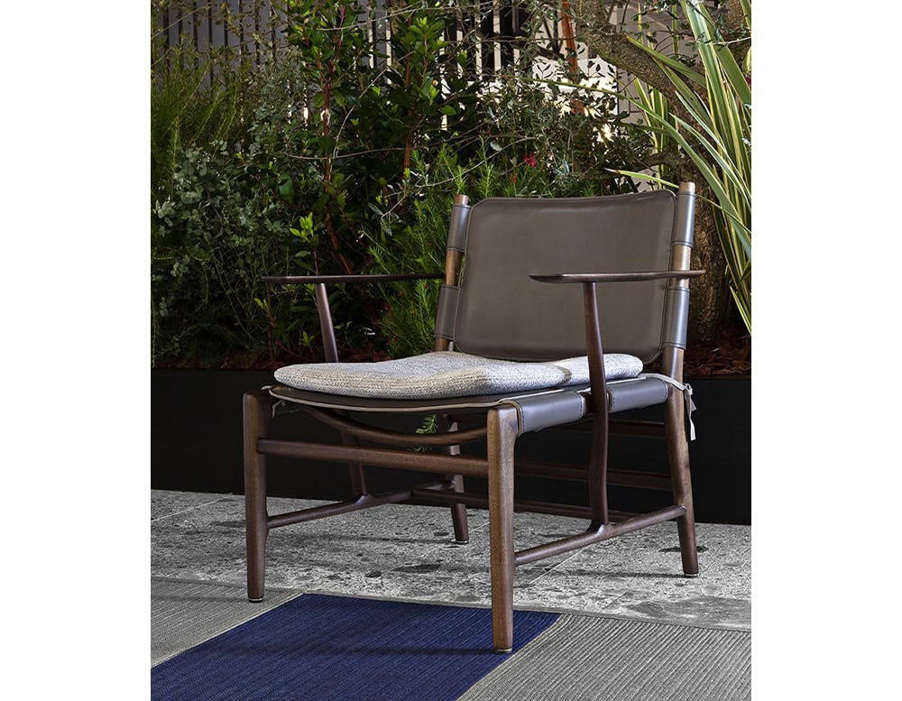 Levante Chair. Structure in brown wood, seat and backrest in black leather with gray cushions on a terrace.