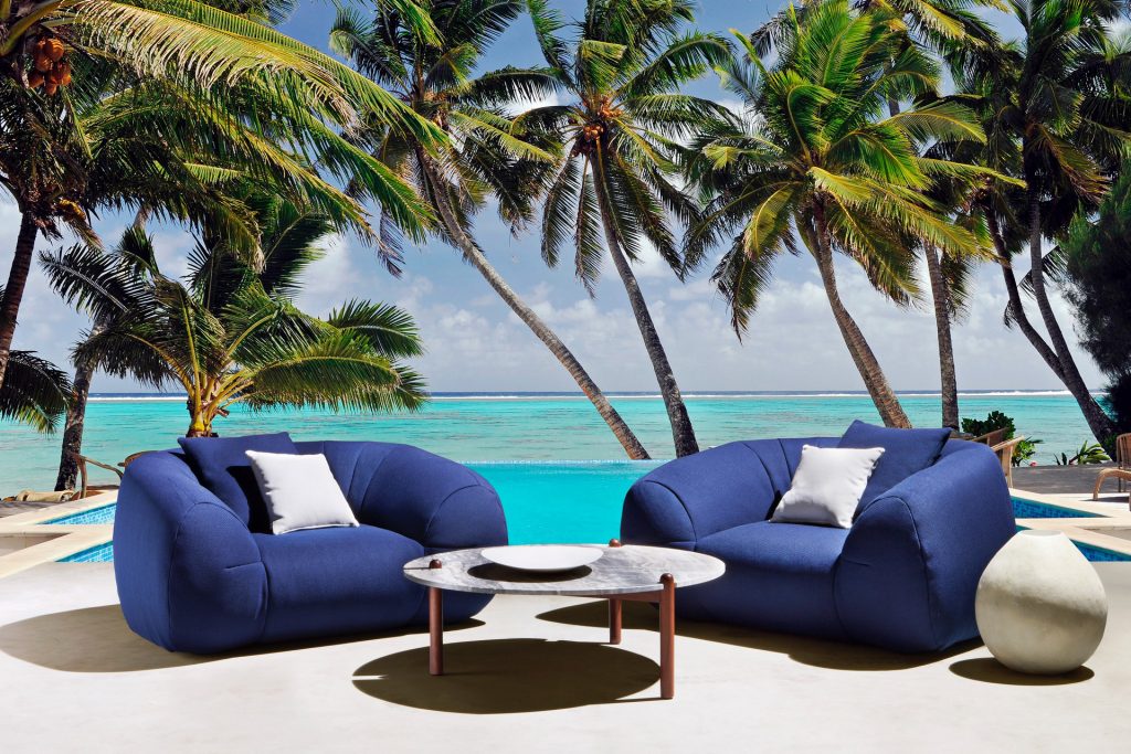 two palau amrchairs in front of a table on a beach