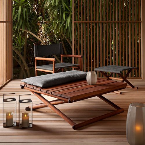 Sqaure Paraggi Coffee Table in brown wood with crossed legs in a living room.