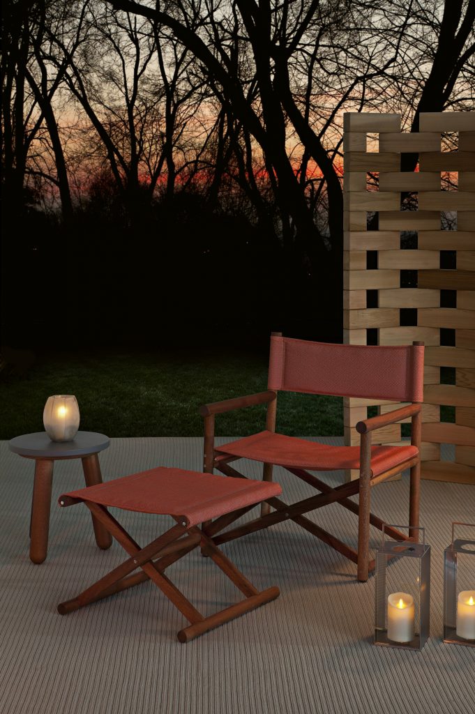 paraggi pouf outdoors in red in front of a red chair and next to some tables