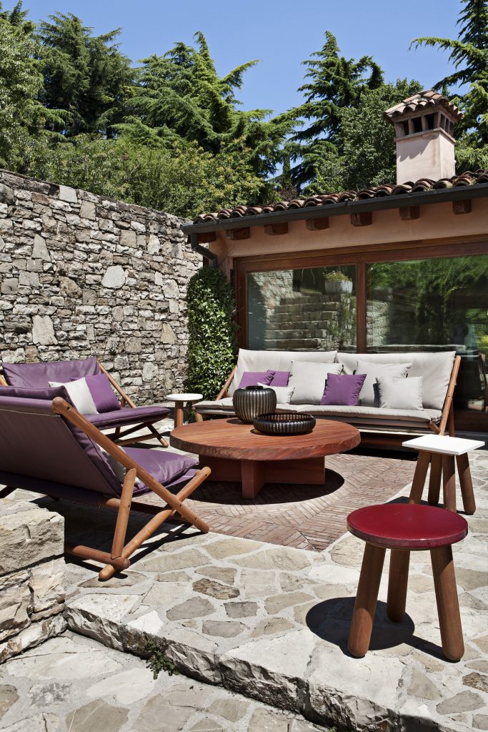 Three Paraggi Sofas upholstered in fabric, two in purple and one in white on a terrace.