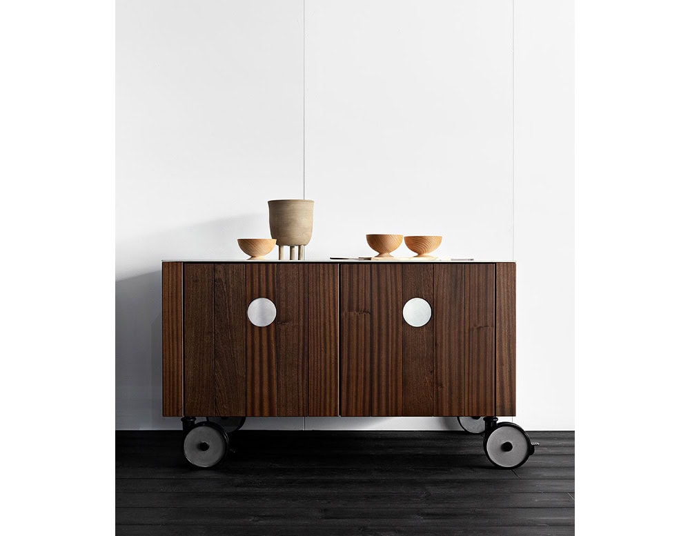 Roller Kitchen cabin covered in brown wooden with four wheels against a wall.