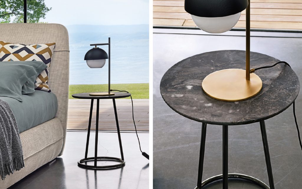 angle tambe in black metal with a small table lamp on top, displayed next to a bed