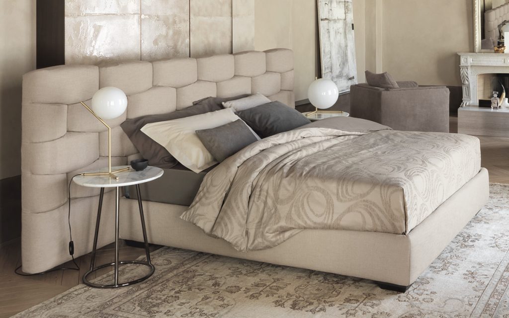 angle small table with metal legs and white marble top with a metal lamp next to a bed