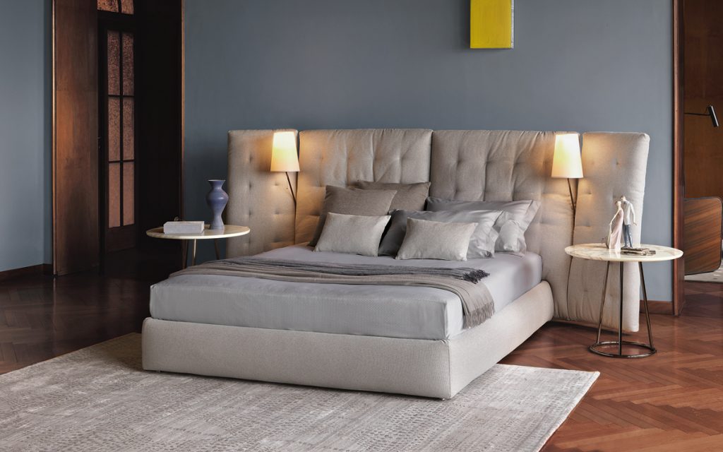 bedroom setting showcasing 2 marble tables in white marble, one has a blue vase the other one has 2 figurines of a couple kissing